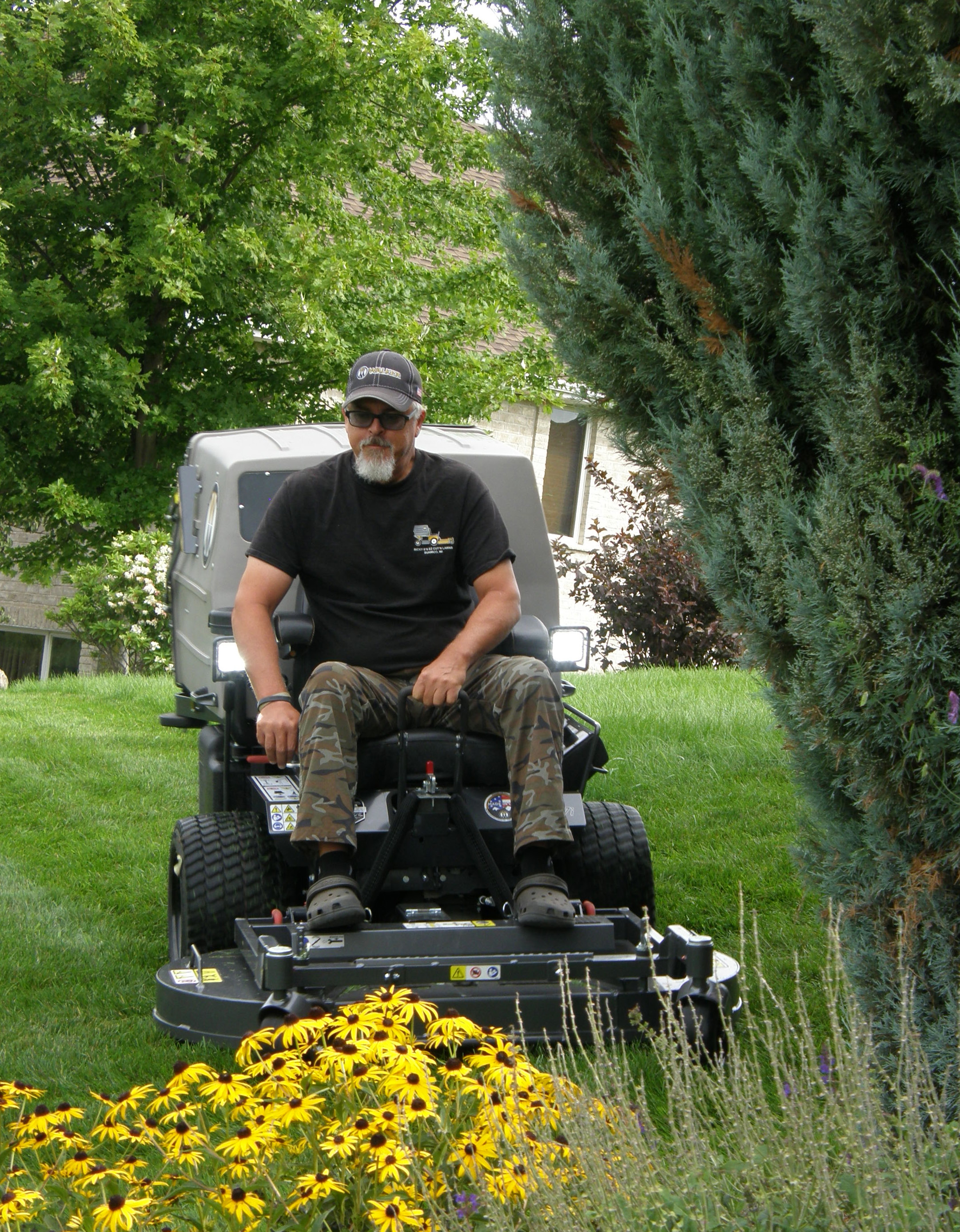 Rick Blosser mowing lawn by sunflowers